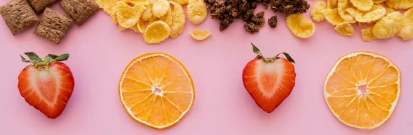 Top view of assorted breakfast cereal corn flakes and crispy granola near fruits isolated on pink, banner — Stock Photo