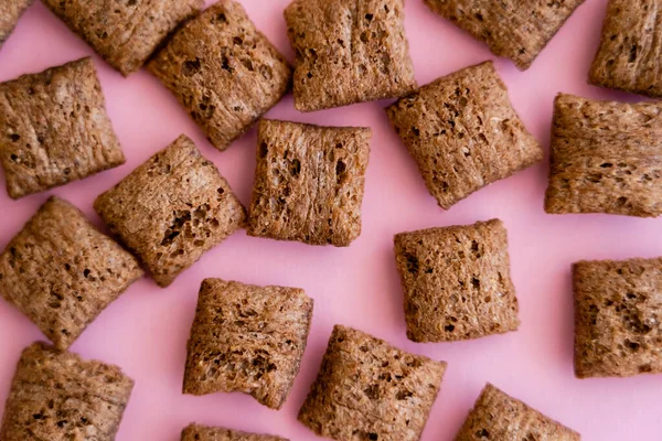 Vista superior de las bocanadas de cereales de desayuno con chocolate aislado en rosa - foto de stock