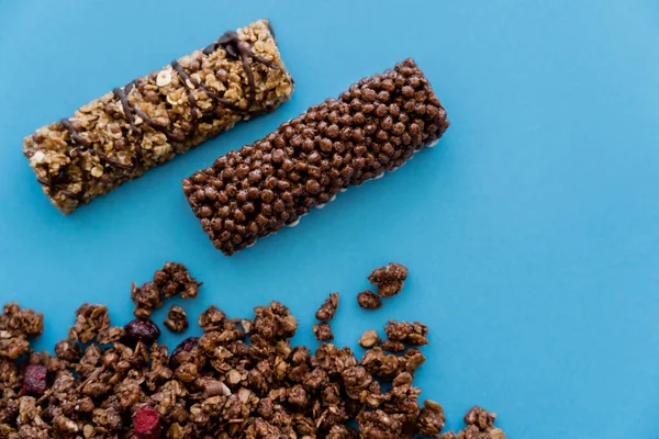 Vue de dessus des barres de granola près du muesli croquant isolé sur bleu — Photo de stock