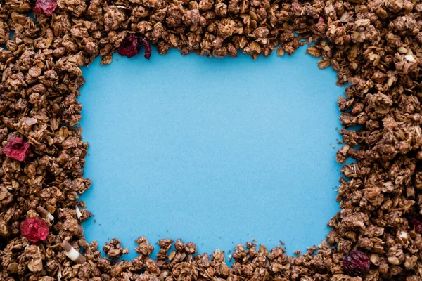 Vista dall'alto di telaio in granola d'avena croccante e dolce isolata su blu — Foto stock