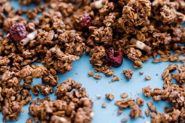 Close up of crunchy granola with dry berry on blue background — Stock Photo