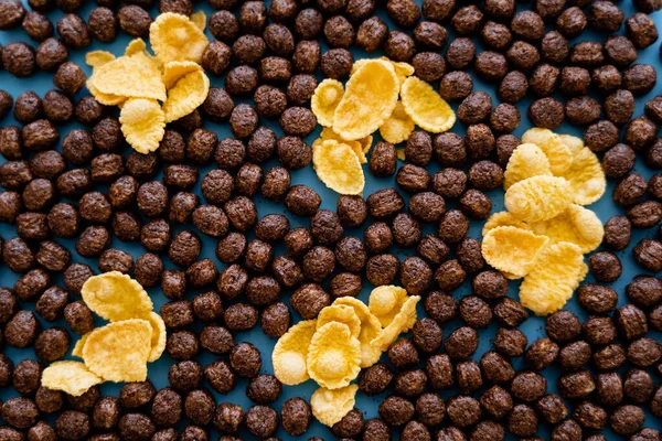 Vista superior de flocos de milho crocante e bolas de cereais de chocolate em azul — Fotografia de Stock