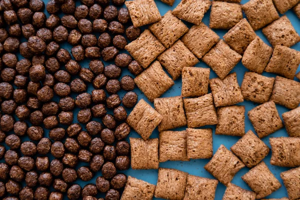 Vue de dessus de savoureuses boules de céréales au chocolat et bouffées sur bleu — Photo de stock