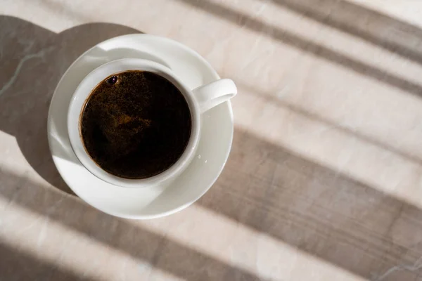 Top view of cup of black coffee and white saucer on marble surface — Stock Photo