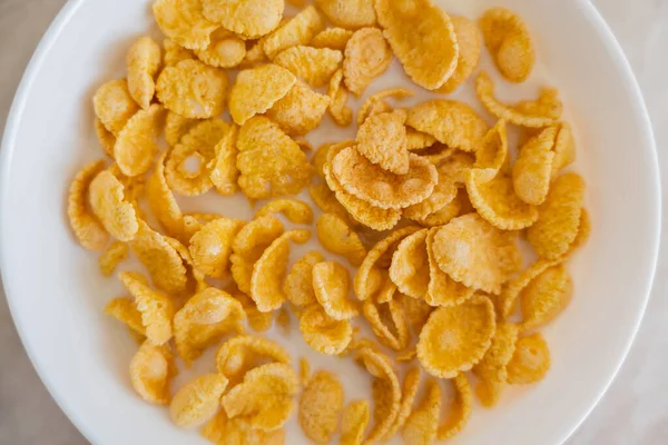 Close up view of bowl with corn flakes and organic milk on marble surface — Stock Photo