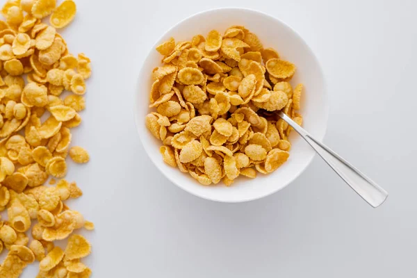 Top view of bowl with corn flakes and spoon isolated on white — Stock Photo