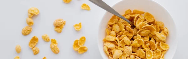 Top view of bowl with crispy corn flakes and spoon isolated on white, banner — Stock Photo