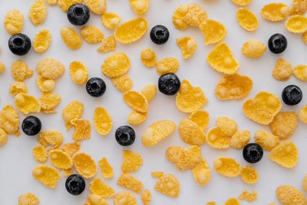 Draufsicht auf knusprige Cornflakes in der Nähe schmackhafter Blaubeeren auf weißem Hintergrund — Stockfoto