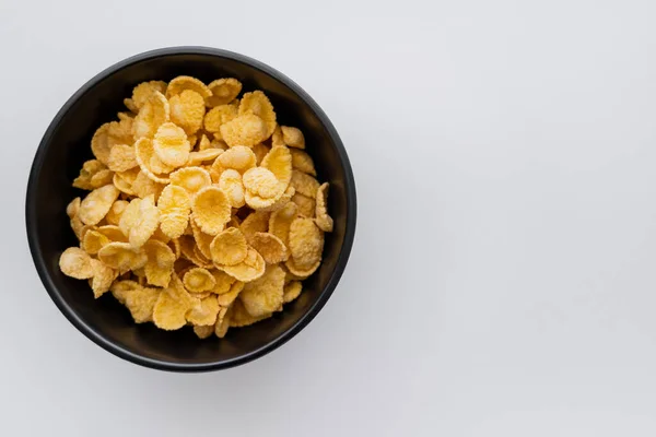 Draufsicht auf schwarze Schüssel mit Cornflakes isoliert auf weiß — Stockfoto