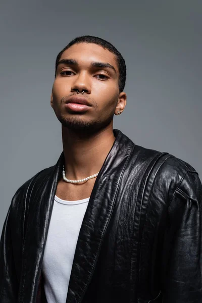 Portrait of young african american man in leather jacket posing isolated on grey — Stock Photo