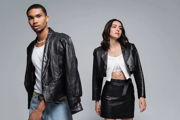 Young interracial couple in stylish autumnal outfits posing isolated on grey — Stock Photo