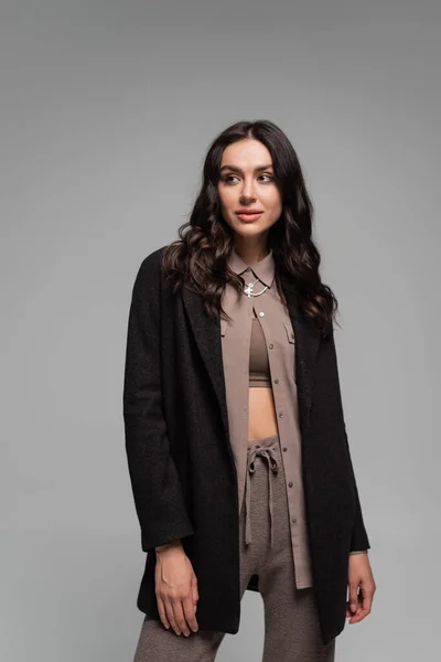 Brunette young woman in black blazer looking away isolated on grey — Stock Photo