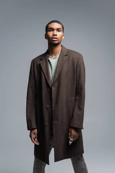 Jeune homme afro-américain en manteau de laine regardant caméra isolée sur gris — Photo de stock