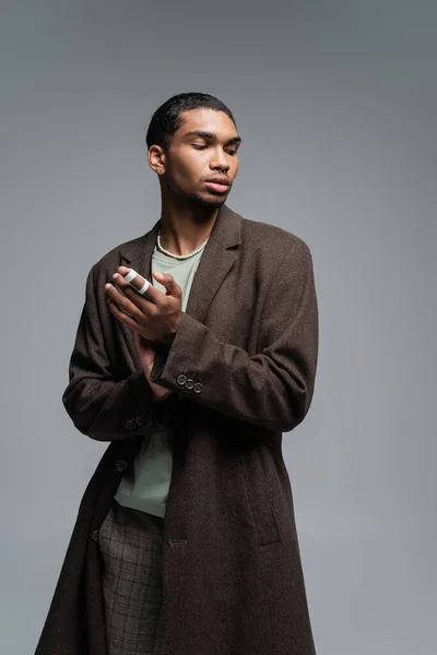 Jovem homem americano africano em casaco de lã outonal olhando para longe isolado em cinza — Fotografia de Stock