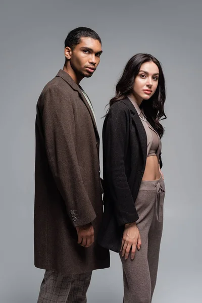 Stylish woman in black blazer near young african american man in woolen coat isolated on grey — Stock Photo