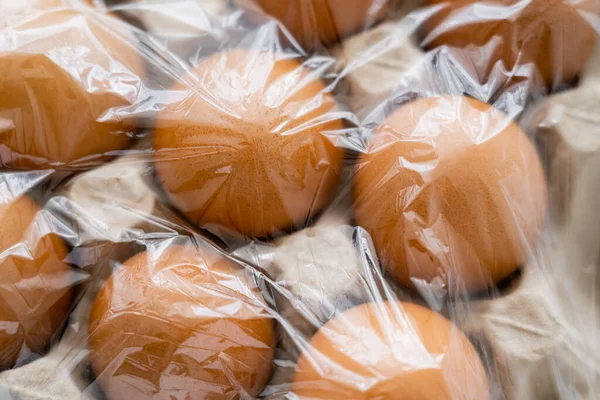 Top view of brown eggs in cardboard container with cellophane — Stock Photo