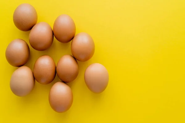 Vista superior de huevos marrones sobre fondo amarillo - foto de stock