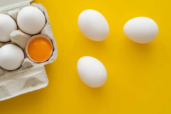 Top view of eggs and yolk in shell in package on yellow background — Stock Photo