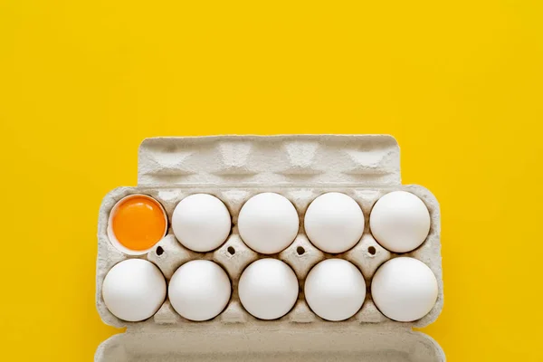 Top view of eggs and yolk in shell in tray isolated on yellow — Stock Photo