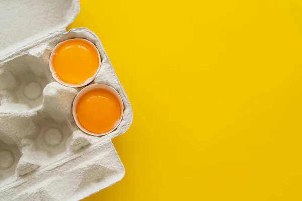 Top view of fresh yolks in shells in egg tray on yellow background — Stock Photo