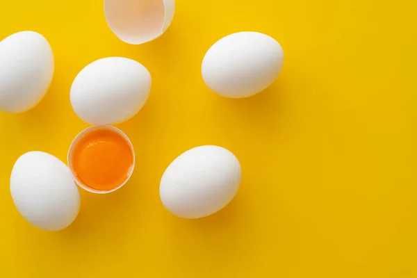 Vista superior de la yema natural en cáscara cerca de los huevos sobre fondo amarillo - foto de stock