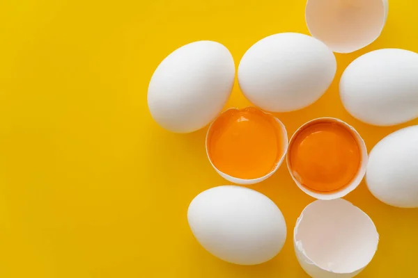 Top view of natural eggs and yolks in shells on yellow background with copy space — Stock Photo