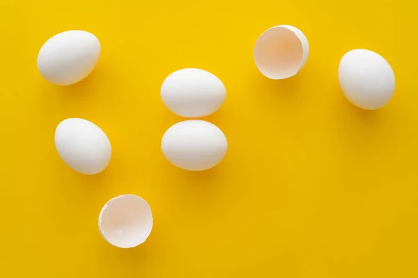 Draufsicht auf weiße Eier und Muscheln auf gelbem Hintergrund — Stockfoto