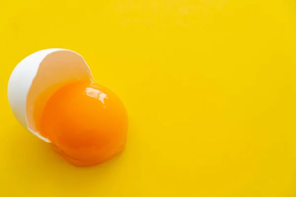 Vista de cerca de la yema de huevo natural cruda en cáscara sobre fondo amarillo - foto de stock