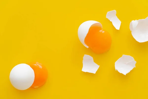 Vue du dessus des jaunes et des coquilles d'œufs blancs sur fond jaune — Photo de stock