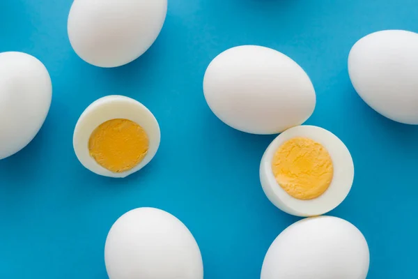 Top view of cut boiled eggs on blue background — Stock Photo