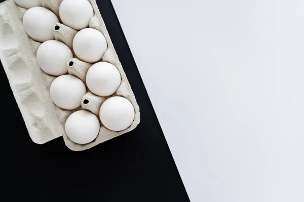 Top view of natural chicken eggs in carton tray on white and black background with copy space — Stock Photo