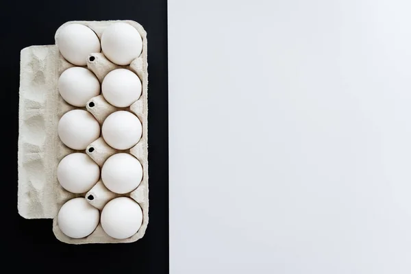 Vue du dessus des œufs de poulet dans un bac en carton sur fond blanc et noir — Photo de stock