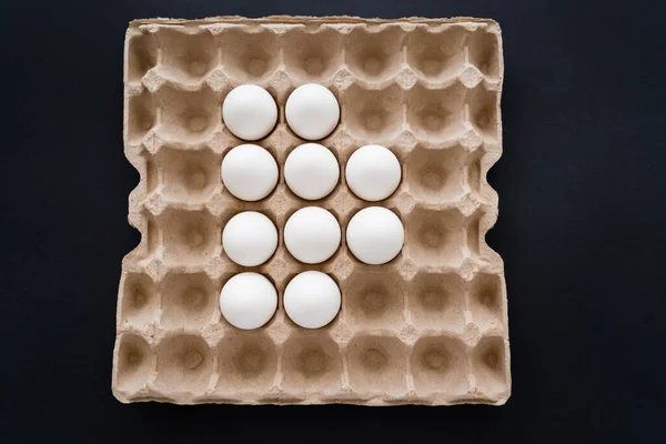 Top view of white eggs in carton package isolated on black — Stock Photo