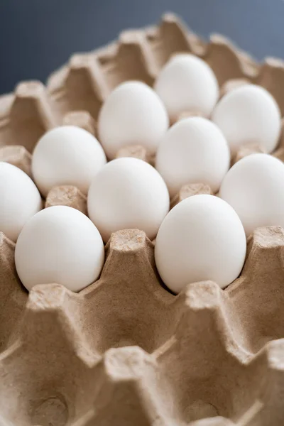 Uova di pollo naturali in vassoio di cartone su sfondo grigio sfocato — Foto stock