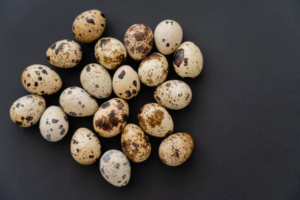Top view of natural quail eggs on black surface — Stock Photo