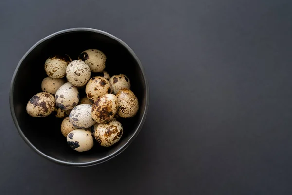 Vista superior de ovos de codorna em tigela no fundo preto com espaço de cópia — Fotografia de Stock