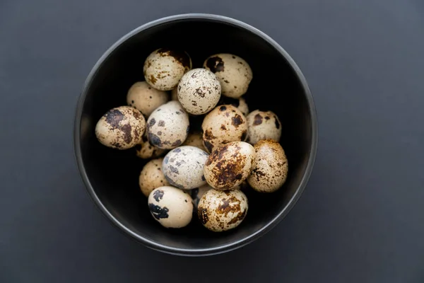 Top view of fresh quail eggs in bowl on black background — Stock Photo