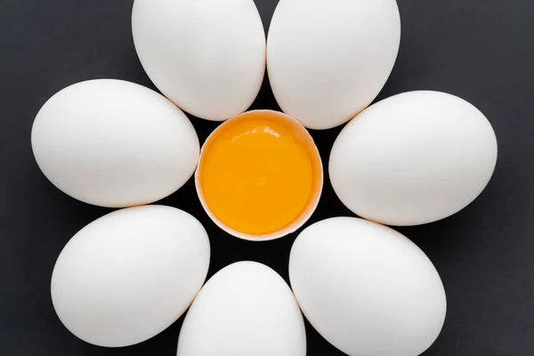 Puesta plana con huevos de pollo con yema en cáscara aislada sobre negro - foto de stock