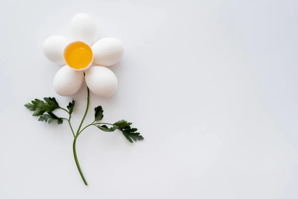 Colocação plana de ovos naturais e salsa em forma de flor no fundo branco — Fotografia de Stock