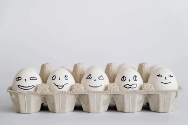 Uova di pollo dipinte con espressioni facciali in vassoio su sfondo bianco — Foto stock