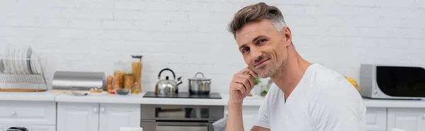 Man looking at camera in blurred kitchen, banner — Stock Photo