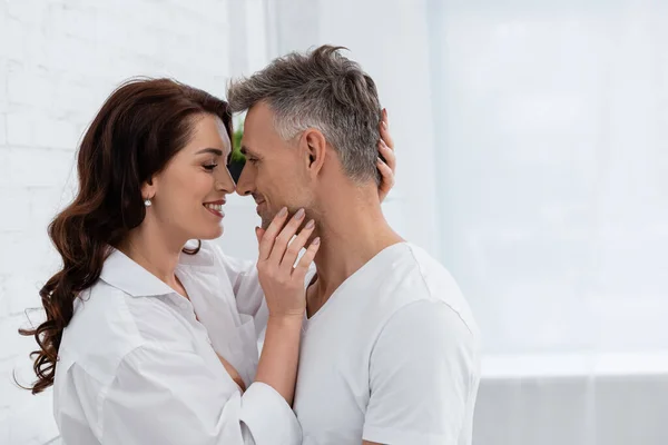 Vista lateral da mulher morena alegre na camisa tocando marido em casa — Fotografia de Stock