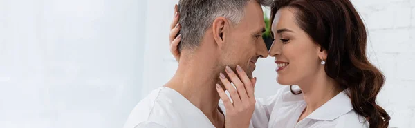 Vue latérale de la femme brune souriante touchant le mari à la maison, bannière — Photo de stock
