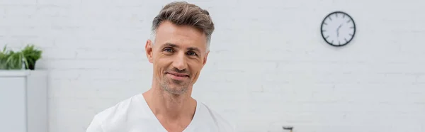 Homem de t-shirt sorrindo para a câmera na cozinha, banner — Fotografia de Stock