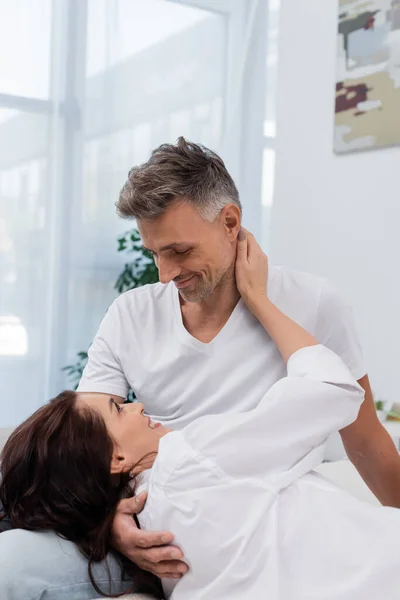 Lächelnde Frau im Hemd berührt Ehemann im Schlafzimmer — Stockfoto