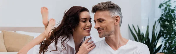 Femme souriante en chemise blanche touchant mari dans la chambre à coucher à la maison, bannière — Photo de stock