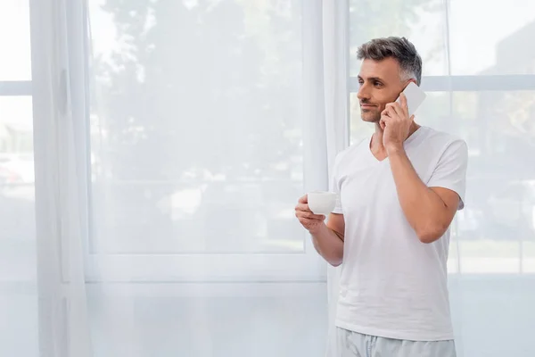 Mann im Pyjama spricht mit Smartphone und hält Tasse zu Hause — Stock Photo