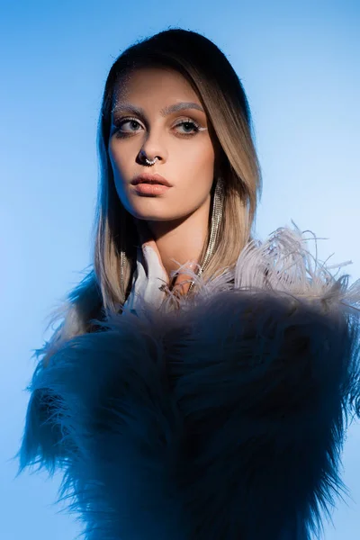 Jeune femme rêveuse avec des sourcils perçants et neigeux sur fond bleu — Photo de stock