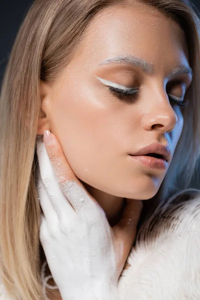 Retrato de mujer rubia joven con maquillaje de invierno posando aislado en azul oscuro - foto de stock