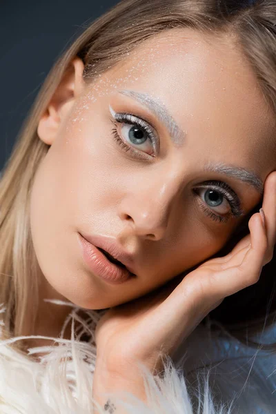 Retrato de jovem loira com maquiagem de inverno olhando para câmera isolada em azul — Fotografia de Stock